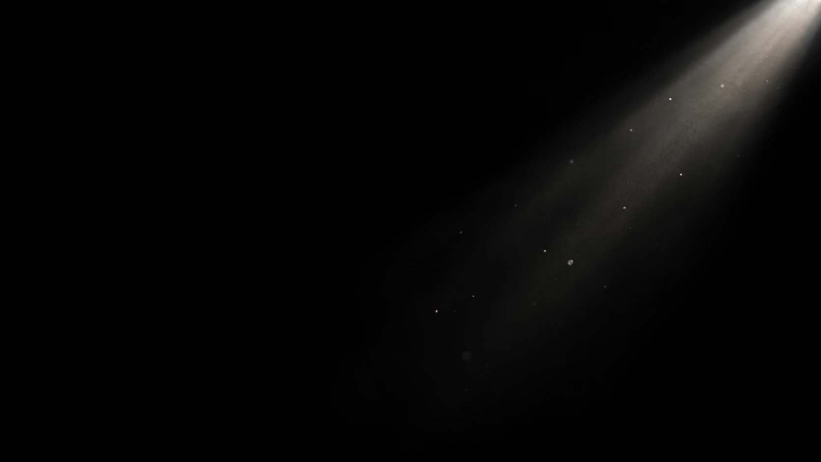 A narrow white shaft of light enters diagonally from a small unseen aperture at the upper right, revealing just a dozen tiny dust motes on black.