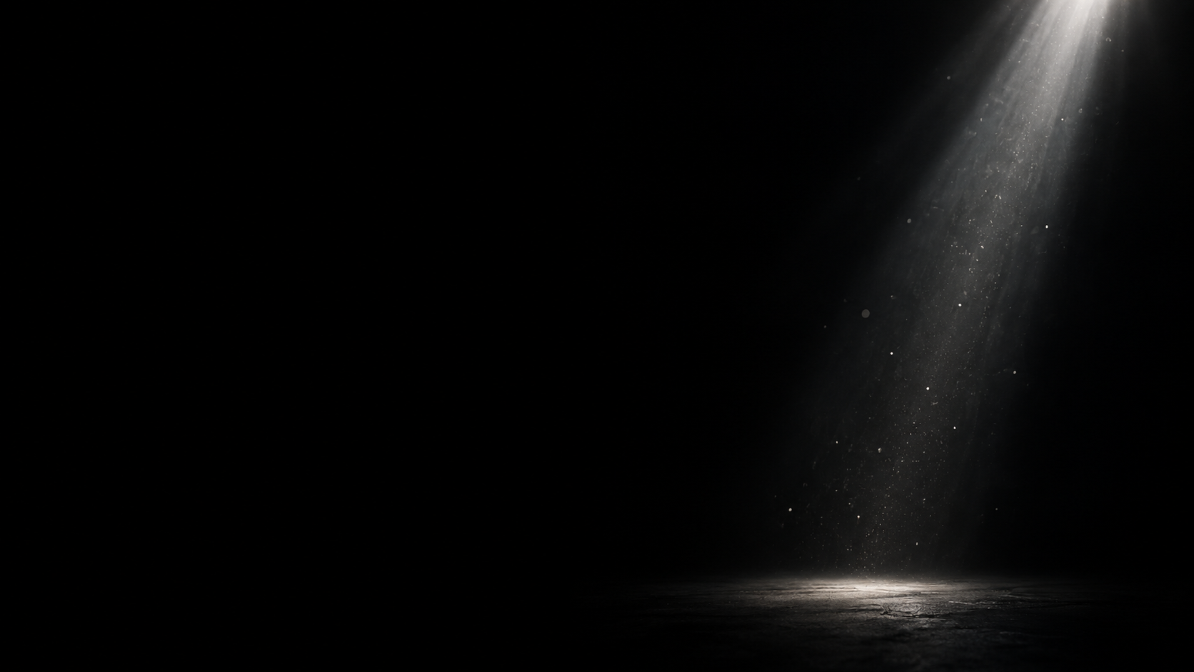 A narrow column of silver light falls from the top right through sparse tiny falling dust, almost all frame black.