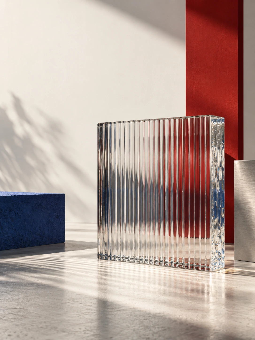 One large ribbed clear glass block refracts a narrow red vertical panel behind it, on a neutral white studio floor.